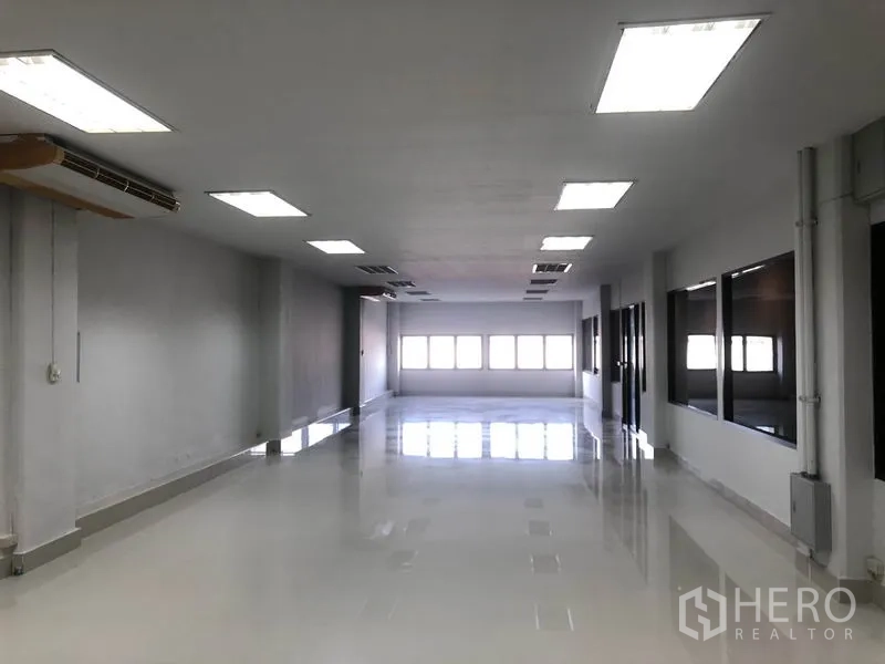 Warehouse for rent in Bang Sao Thong, Samut Prakan - Large open-plan office with bright ceiling lights and a windowed wall.