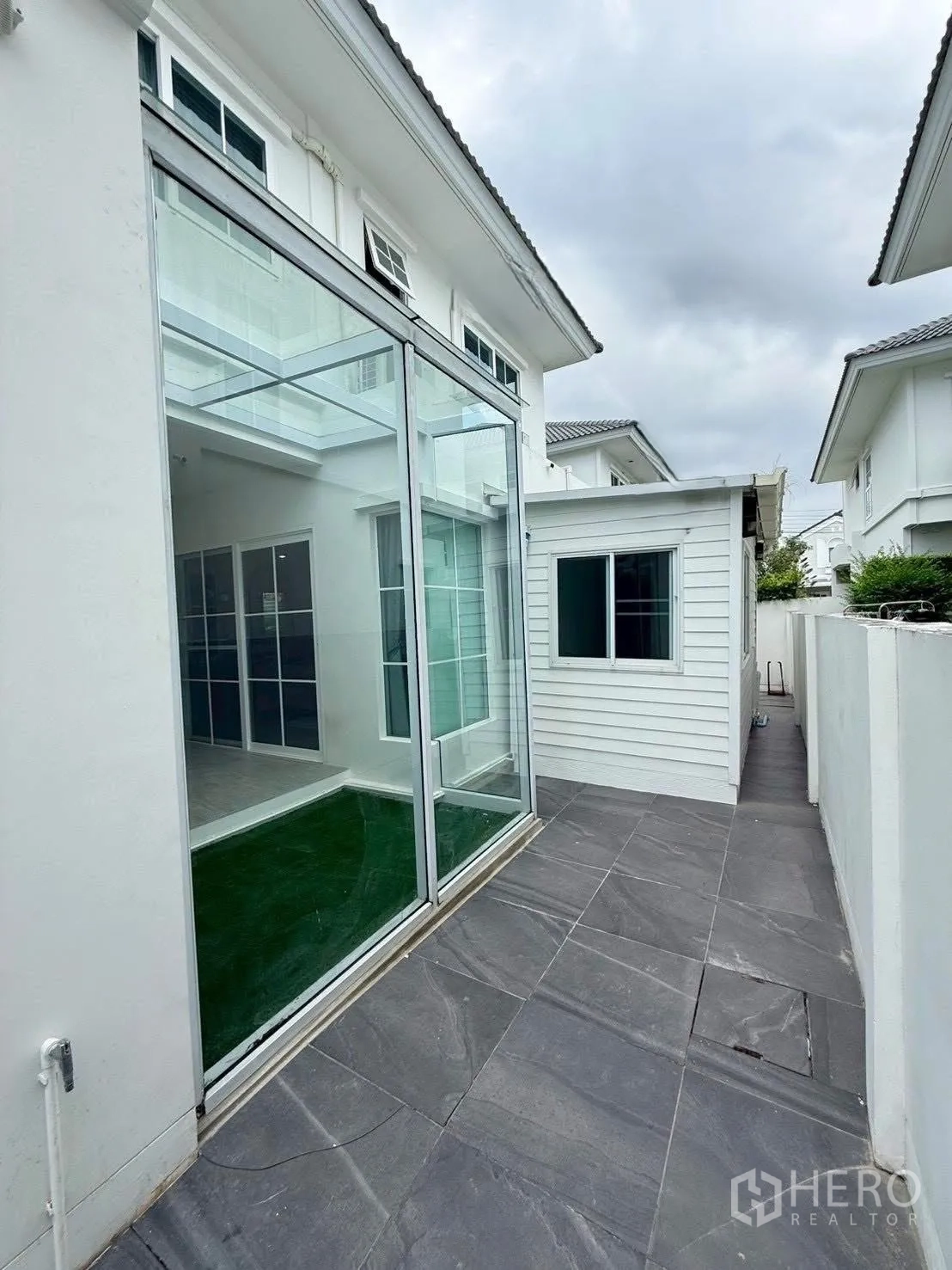 Detached House for rent in Bang Phli, Samut Prakan - Side terrace with dark tiles and large sliding glass walls.