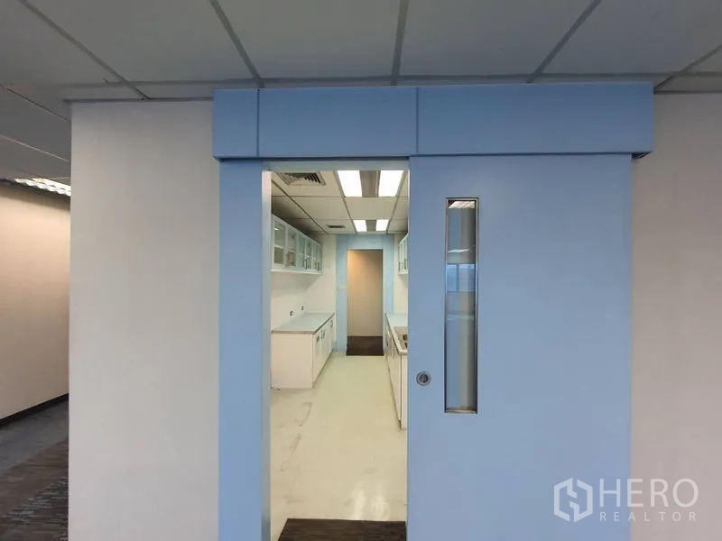 办公空间 出租在Watthana, Bangkok - 滑动门通向明亮茶水间，白色橱柜与日光灯顶。