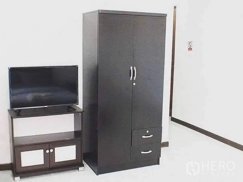 Shophouse for sale in Lam Luk Ka, Pathum Thani - Furnished room with dark wardrobe and TV on cabinet.