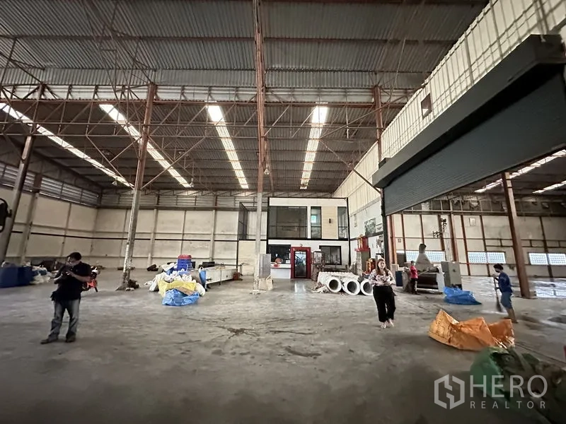 工厂 出租在Bang Bua Thong, Nonthaburi - 宽阔厂房地面，内置办公区与卷帘门。