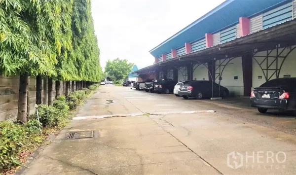 โรงงาน ขายในLam Luk Ka, Pathum Thani - ชานโหลดสินค้าพร้อมหลังคาคลุม ที่จอดรถ และแนวต้นไม้สูงช่วยบังสายตา