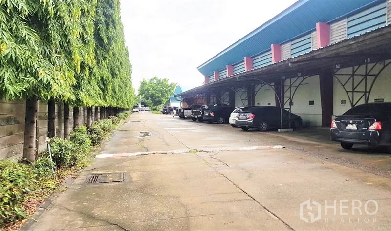 โรงงาน ขายในLam Luk Ka, Pathum Thani - ชานโหลดสินค้าพร้อมหลังคาคลุม ที่จอดรถ และแนวต้นไม้สูงช่วยบังสายตา