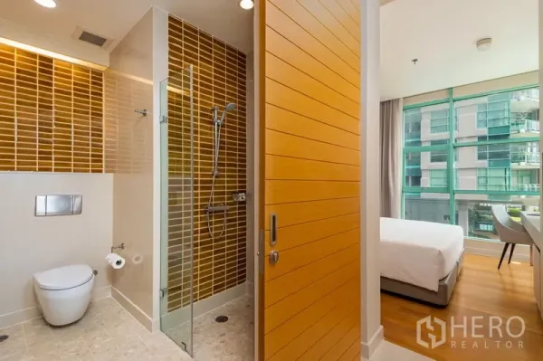 คอนโด ให้เช่าในBang Kho Laem, Bangkok - ห้องน้ำสมัยใหม่พร้อมตู้ shower กระจก กระเบื้องสีน้ำตาล โถสุขภัณฑ์แขวน และทางเข้าห้องนอนที่สว่างด้วยหน้าต่างเต็มผนัง