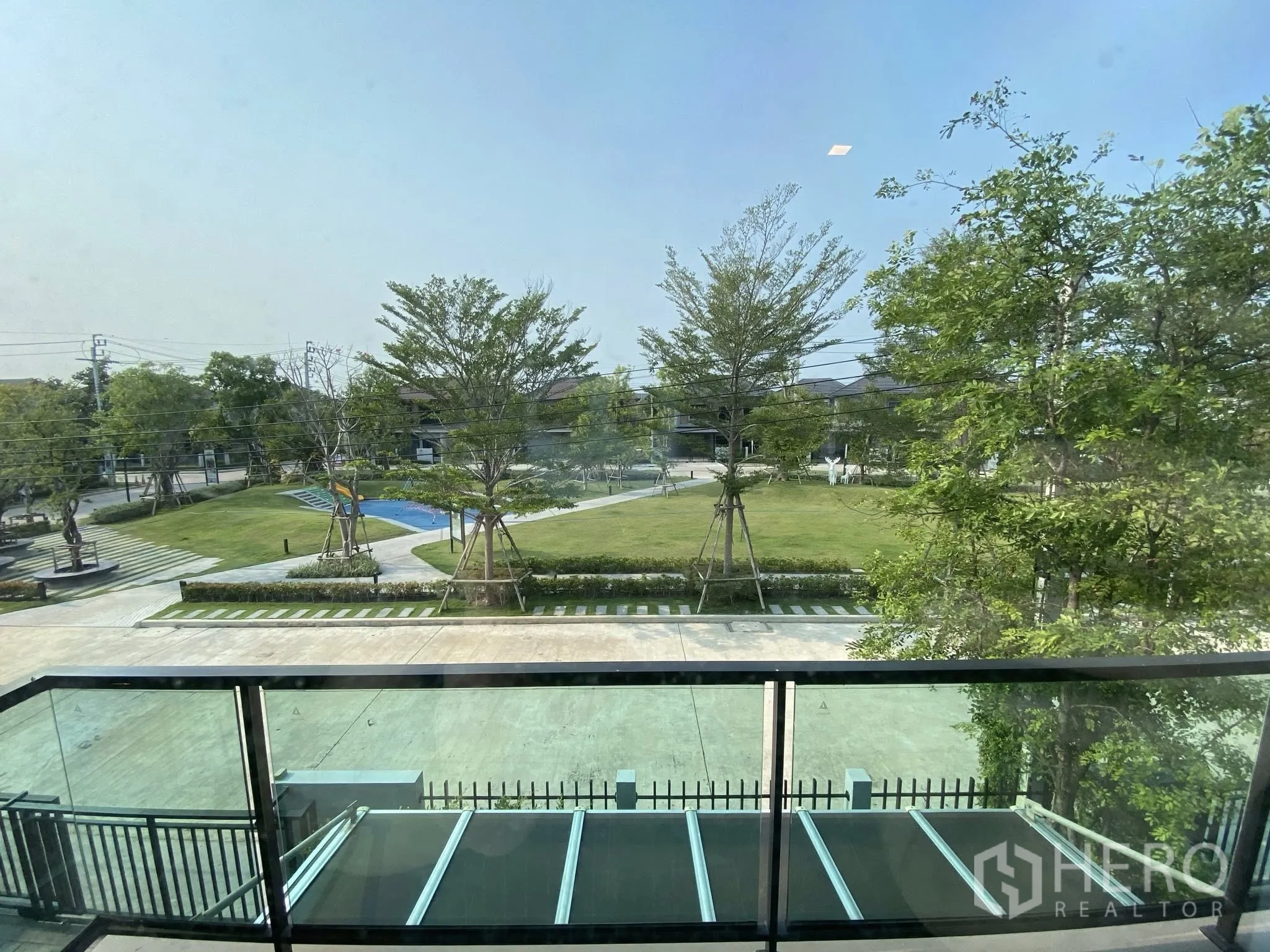 Detached House for sale in Saphan Sung, Bangkok - Balcony with glass railing overlooking community park and playground.
