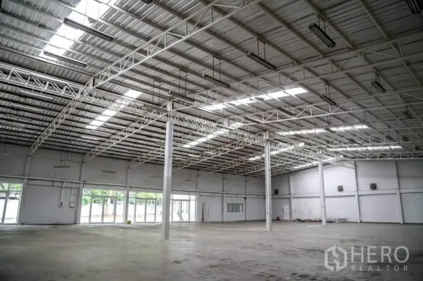 Warehouse for rent in Din Daeng, Bangkok - Spacious warehouse interior with high steel-truss roof, skylights, multiple pillars and polished concrete floor.