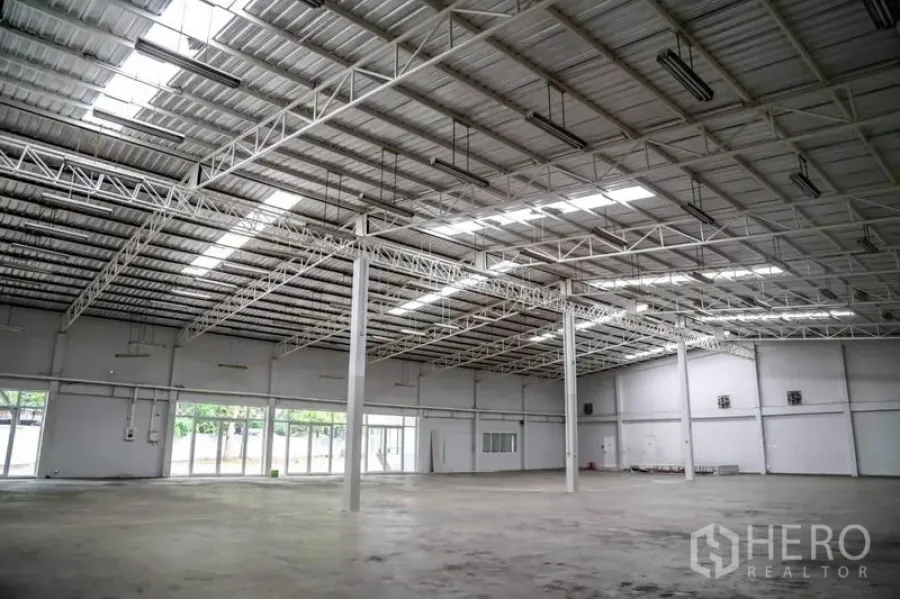 Warehouse for rent in Din Daeng, Bangkok - Spacious warehouse interior with high steel-truss roof, skylights, multiple pillars and polished concrete floor.