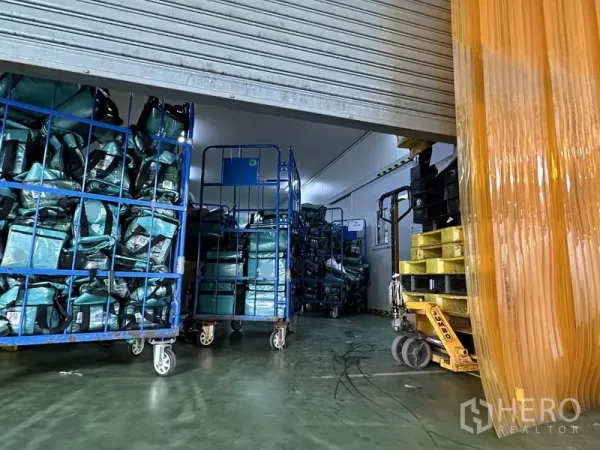 Factory for rent in Lat Krabang, Bangkok - Cold room entrance with rolling door, cage trolleys and a pallet jack on epoxy flooring.