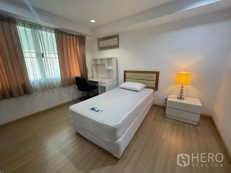 อพาร์ทเมนท์ ให้เช่าในKhlong Toei, Bangkok - ห้องนอนที่สองพร้อมเตียงเดี่ยว โต๊ะทำงาน และโคมไฟข้างเตียง