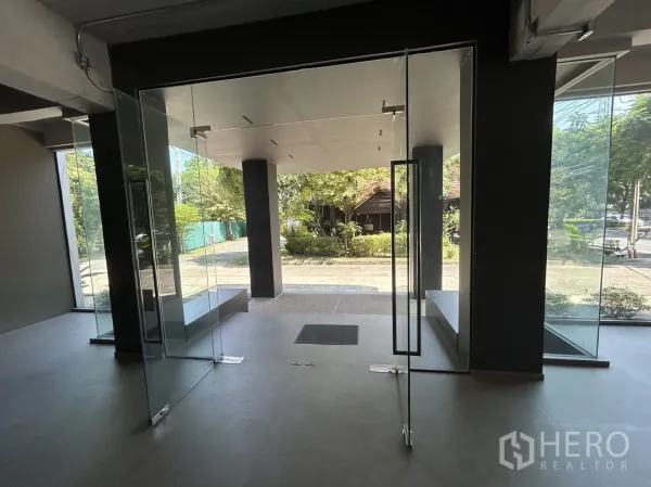 零售空间 出租在Suan Luang, Bangkok - 从室内透过双扇玻璃门望向景观前庭与道路的视角。