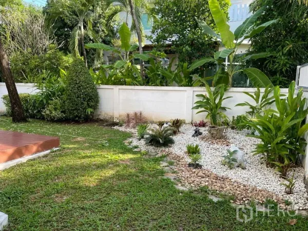 独立式住宅 出租在Prawet, Bangkok - 花园一角，白色卵石景观与茂密植被。