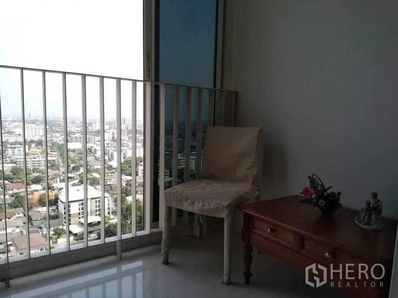 Condominium for rent in Watthana, Bangkok - Balcony seating corner with chair and side table overlooking Bangkok city views.