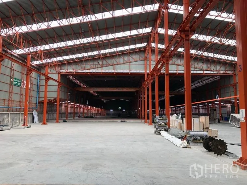 Warehouse for rent in Samut Prakan - Long central aisle showing wide-span steel structure and loading zones in the warehouse.