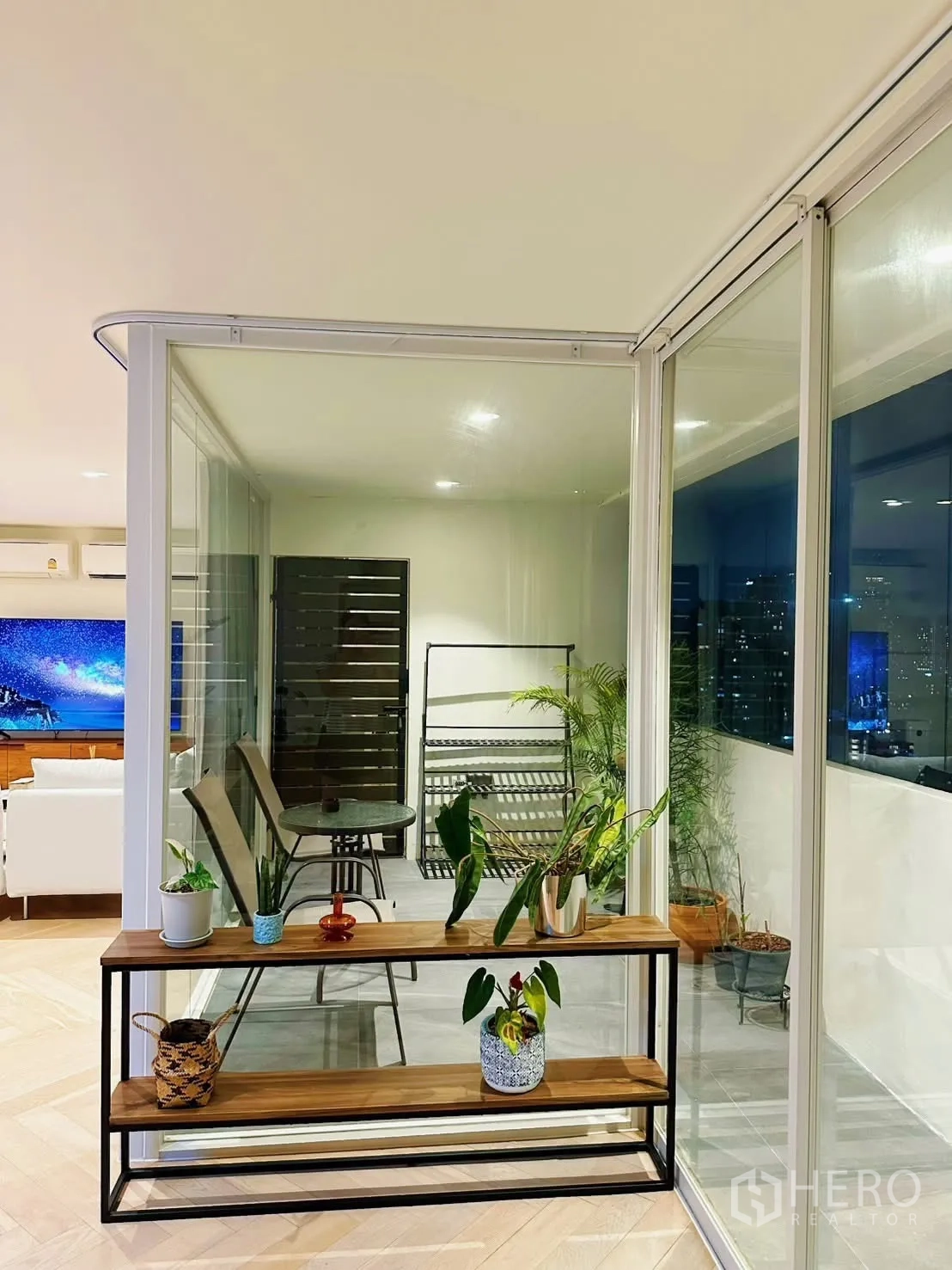 Condominium for rent or sale in Watthana, Bangkok - Enclosed balcony corner with glass walls and a plant display shelf.