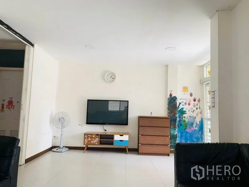 联排别墅 出租或出售在Huai Khwang, Bangkok - 宽敞起居区，墙挂电视、时钟、抽屉柜及大窗户