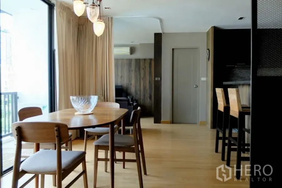 Condominium for sale in Watthana, Bangkok - Dining area and breakfast bar opening to the balcony through sliding glass doors.