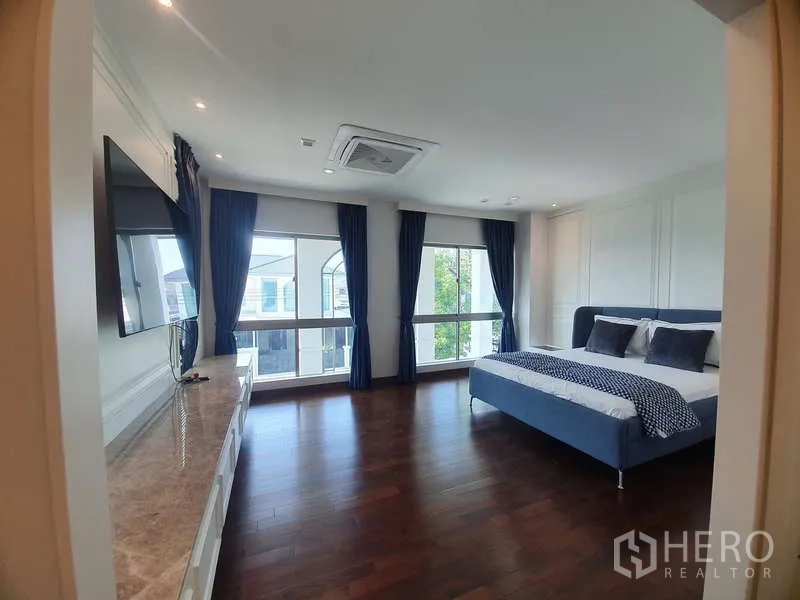 บ้าน ให้เช่าหรือขายในLat Krabang, Bangkok - ห้องนอนมาสเตอร์กว้าง พื้นไม้ หน้าต่างบานใหญ่ ผ้าม่านทึบ และผนังทีวี