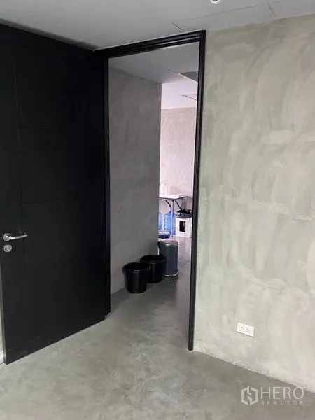 Office Space for rent in Khlong Toei, Bangkok - Entrance to a private room with a dark door and textured concrete walls.