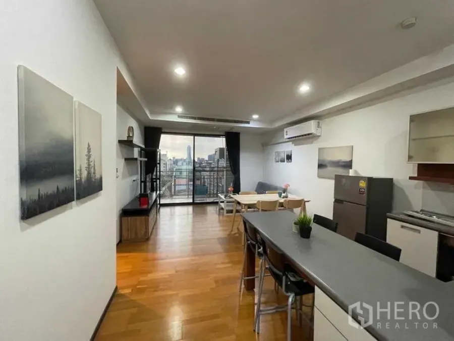 Condominium for rent in Din Daeng, Bangkok - Kitchen island with bar stools beside open living room and balcony city view.
