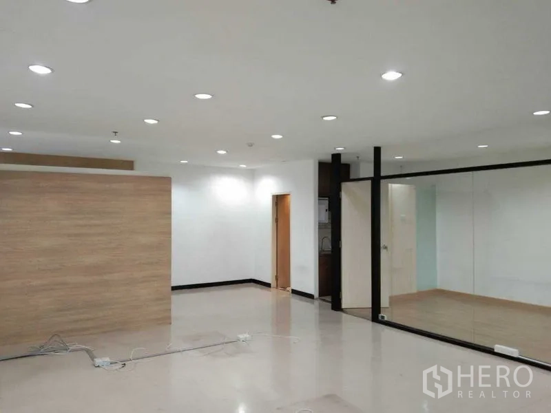Office Space for rent in Watthana, Bangkok - Open office area with a wood feature partition, doorway to pantry, and a mirrored glass wall.
