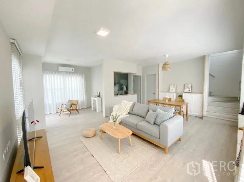 独立式住宅 出租在Prawet, Bangkok - 开放式客餐厅，灰色沙发与纱帘营造明亮空间