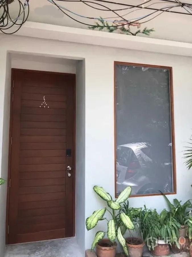 Detached House for rent in Phra Nakhon, Bangkok - House entrance with a wooden door, large window, and potted plants.