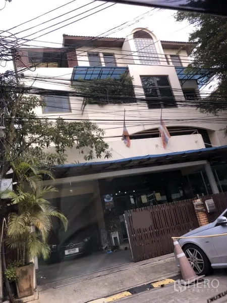 สำนักงานที่บ้าน ขายในHuai Khwang, Bangkok - อาคารโฮมออฟฟิศหลายชั้นในห้วยขวาง กรุงเทพฯ มีกันสาดกระจก ระเบียง ที่จอดรถพร้อมประตูรั้ว และต้นไม้ริมถนน