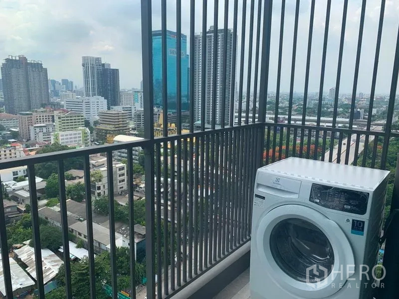 Condominium for rent in Watthana, Bangkok - High-floor balcony with washing machine and expansive skyline view over Sukhumvit.