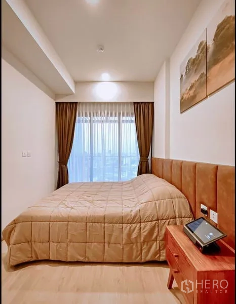 Condominium for sale in Chatuchak, Bangkok - Cozy bedroom with padded headboard, curtains and floor-to-ceiling window.