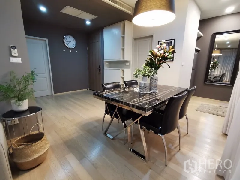 公寓 出售在Bangkok - 餐区配吊灯与大理石桌，内置收纳柜及走廊入口。