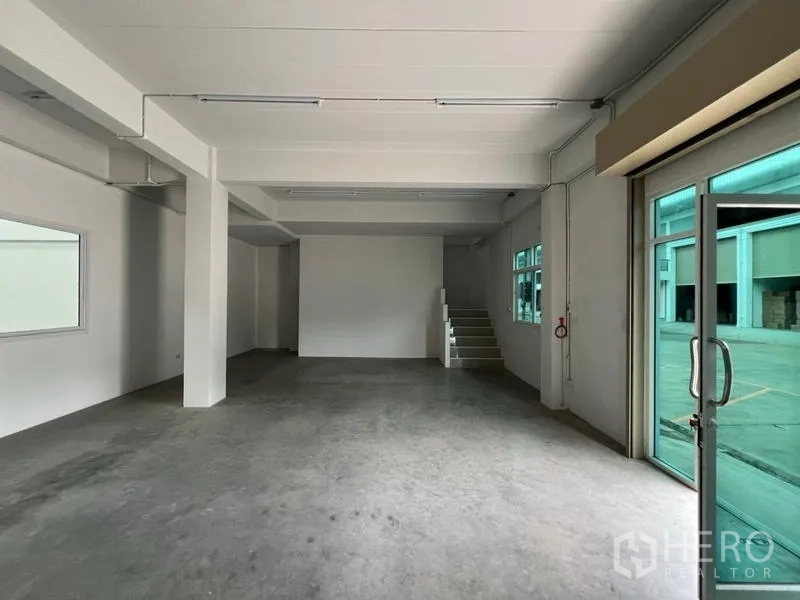 โรงงาน ให้เช่าในPhra Samut Chedi, Samut Prakan - โถงชั้นล่างสำหรับต้อนรับหรือทำงาน มีประตูกระจก พื้นคอนกรีต และบันไดขึ้นชั้นลอย