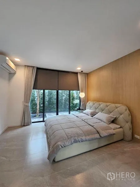 Detached House for rent - Serene bedroom with padded headboard, wood accent wall and garden view.