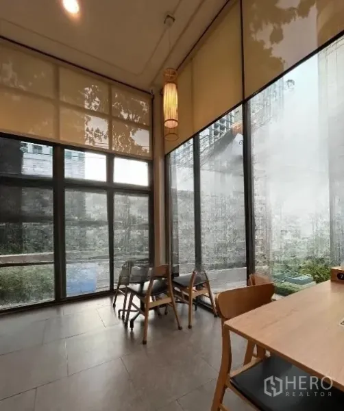 零售空间 出租在Watthana, Bangkok - 靠落地玻璃的角落座位，临小庭院，光线柔和并配卷帘。