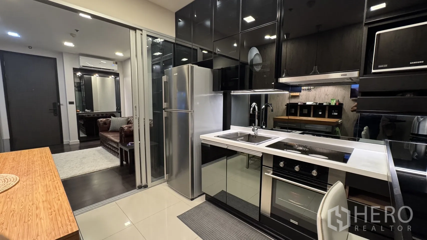 公寓 出租或出售在Khlong Toei, Bangkok - 从厨房望向客厅，可见双水槽、嵌入式烤箱与移门隔断。