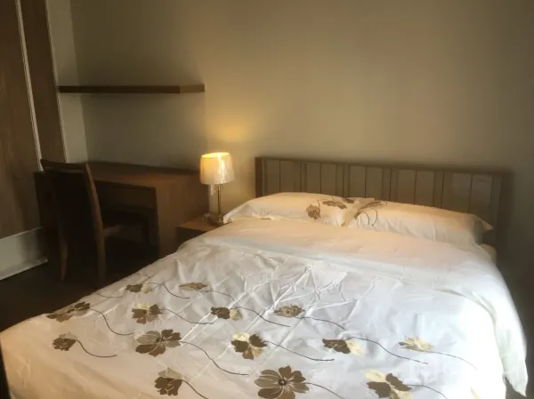 公寓 出租或出售在Khlong Toei, Bangkok - 温馨卧室特写，花卉床品、木质书桌和台灯