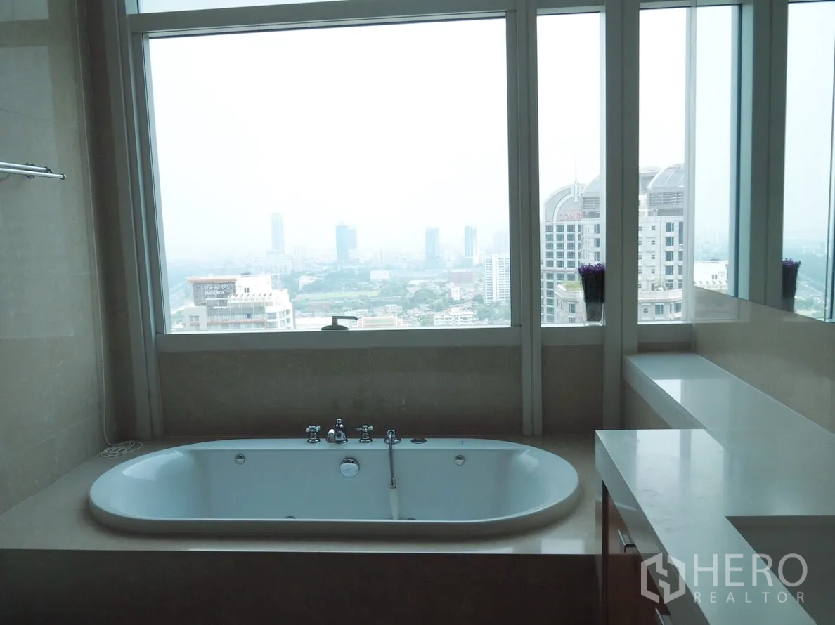 Condominium for rent in Pathum Wan, Bangkok - Spa‑style bathroom with a built‑in bathtub set below large windows offering skyline views.