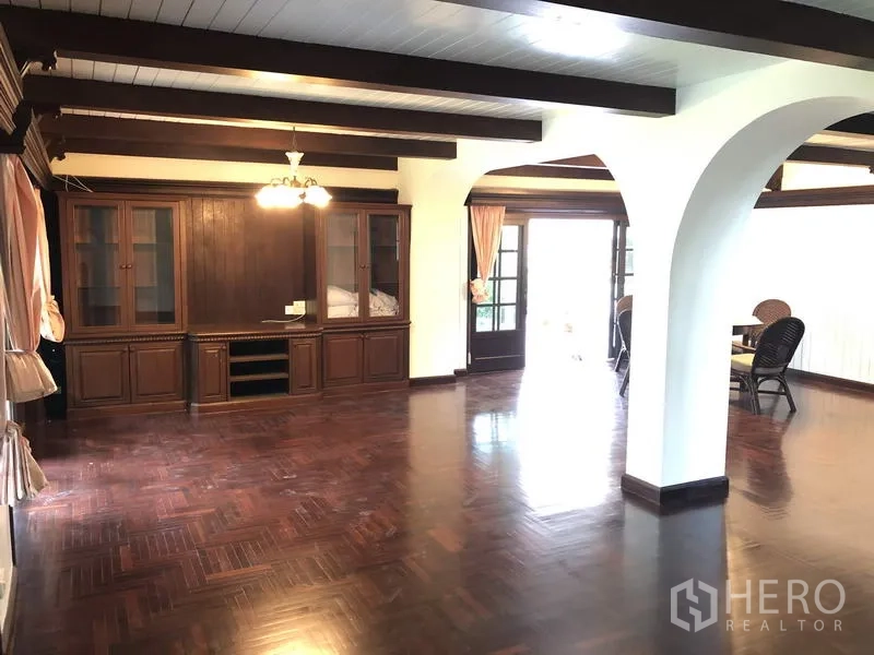 บ้าน ให้เช่าในKhan Na Yao, Bangkok - ห้องนั่งเล่นกว้าง พื้นไม้เข้ม คานไม้โชว์ ตู้บิวท์อิน และประตูกระจกบานฝรั่งเศส.