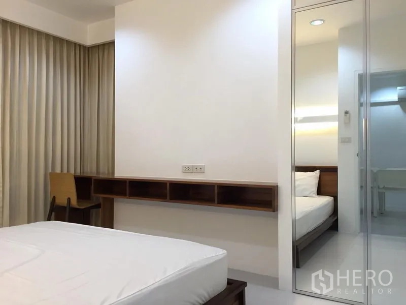 Condominium for rent in Bang Rak, Bangkok - Bright bedroom with a work desk, floor-to-ceiling curtains and a mirrored wardrobe.