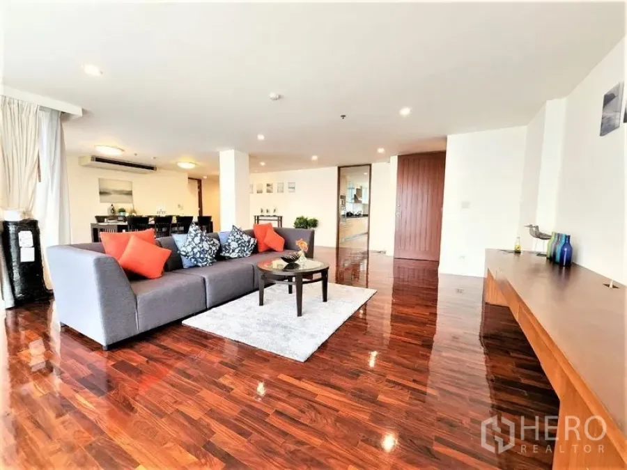 Condominium for rent in Bang Rak, Bangkok - Generous living room with gray sofa, coffee table and bright city-facing windows.
