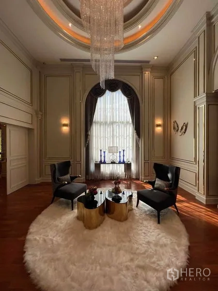 Detached House for rent or sale in Thawi Watthana, Bangkok - Double-height living room with crystal chandelier, arched window and a plush round rug.