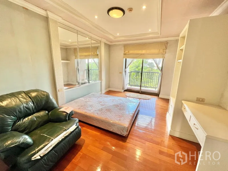 คอนโด ขายในPak Kret, Nonthaburi - ห้องนอนรองสว่าง โปร่ง มีระเบียง ตู้กระจกบานใหญ่ และเก้าอี้หนัง