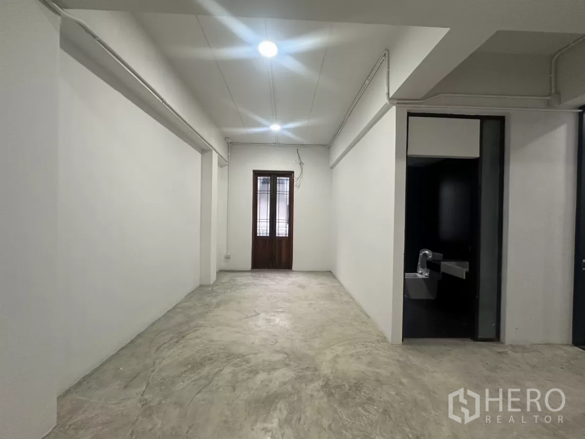 带办公室的家 出租在Pathum Wan, Bangkok - 狭长房间，白墙，通向黑砖卫浴的门洞，尽头为木门。