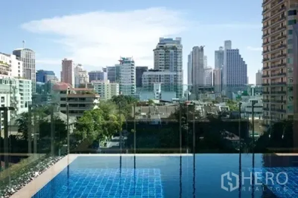 Condominium for rent or sale in Watthana, Bangkok - Rooftop swimming pool with glass railing overlooking the Sukhumvit Bangkok skyline.