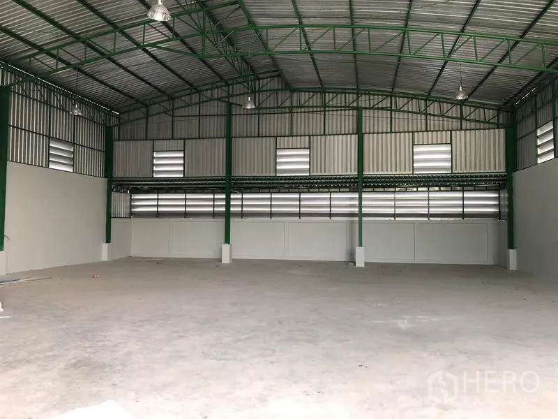 Factory for rent or sale in Khlong Luang, Pathum Thani - Spacious warehouse interior with high ceiling, green steel trusses, and a concrete floor.