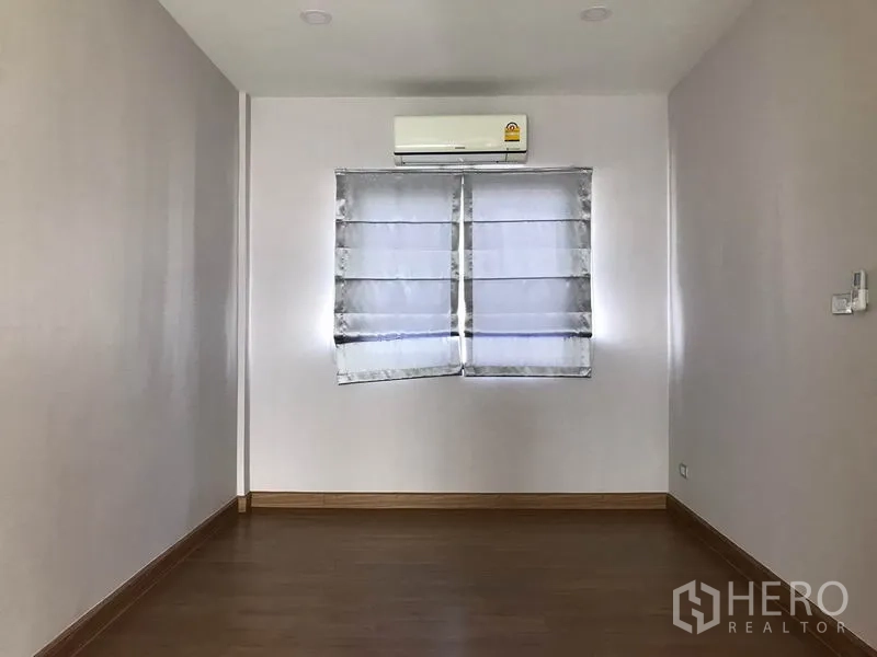 Detached House for rent in Bang Phli, Samut Prakan - Empty bedroom with wood floors, Roman shade and wall AC.