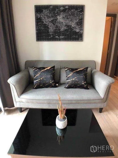 คอนโด ให้เช่าในWatthana, Bangkok - โซฟาสีเทาพร้อมหมอนลายหินอ่อนและโต๊ะกลางกระจกสีดำ ในมุมนั่งเล่น