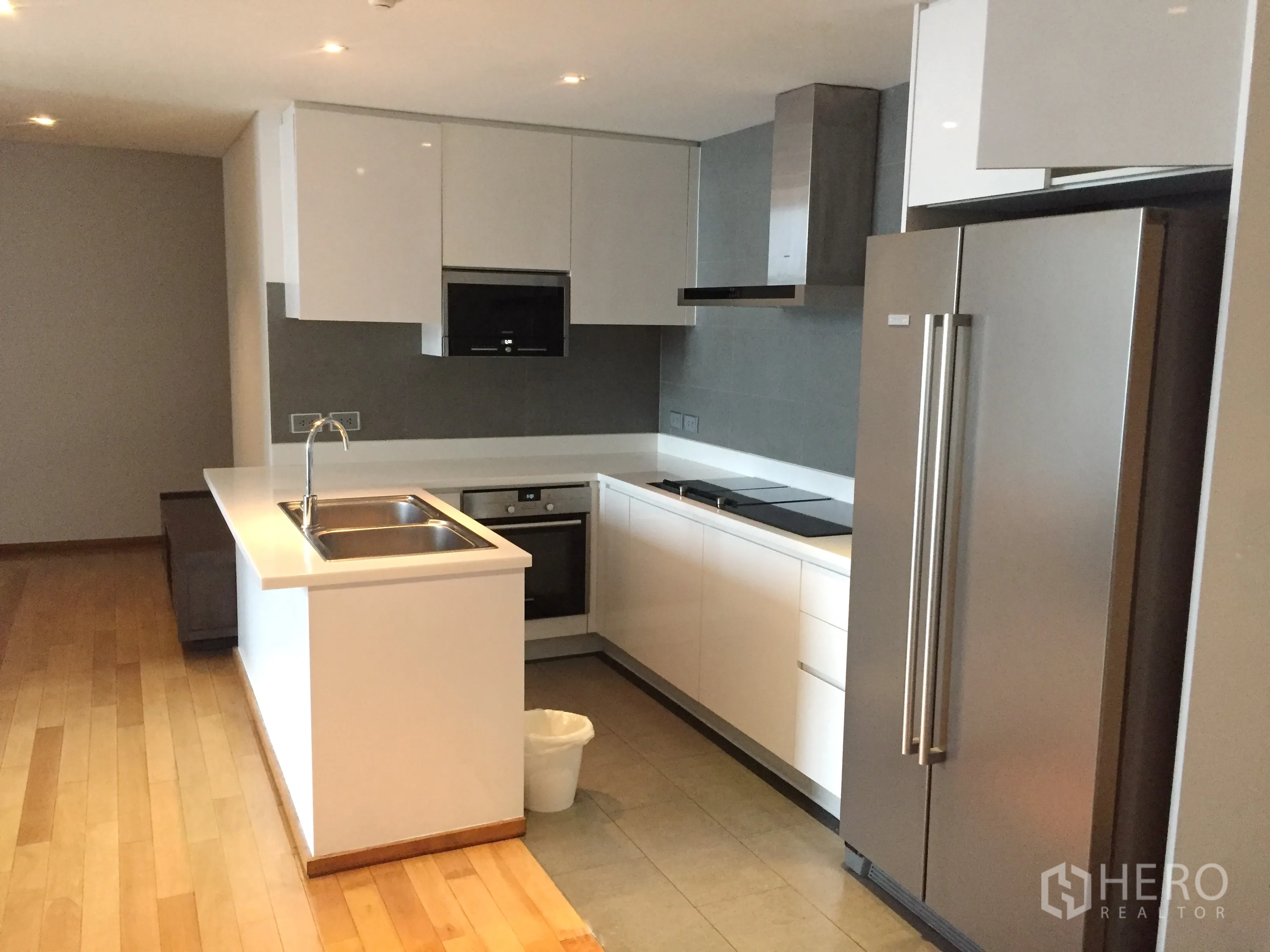 Condominium for rent or sale in Watthana, Bangkok - Modern open kitchen with island sink, built-in oven, cooktop and double-door fridge.