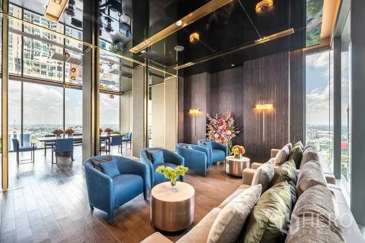 公寓 出租或出售 - 高楼层休息区，蓝色单椅、木地板与城市全景。