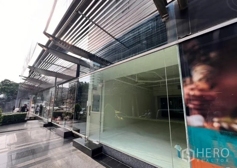 零售空间 出租在Watthana, Bangkok - 金属遮阳与整面玻璃立面的外观，店前为抛光广场。