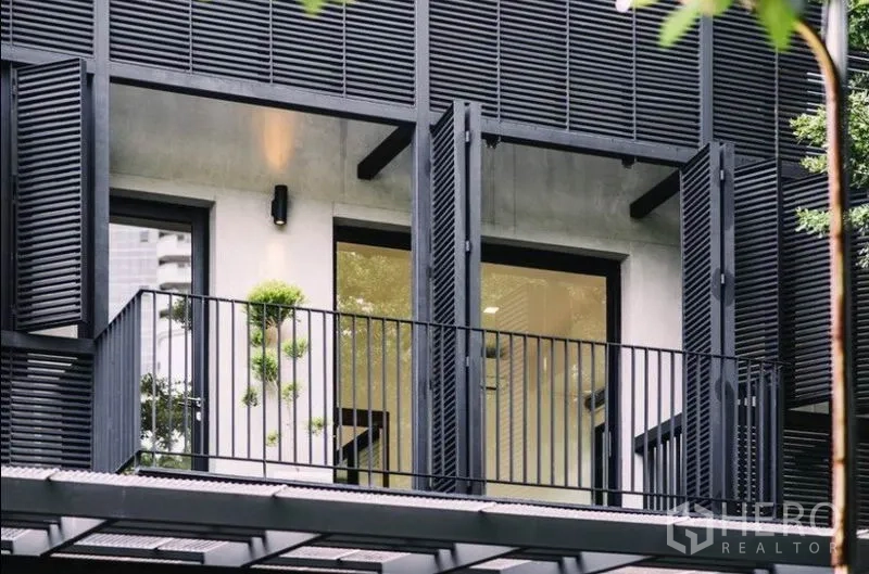 ทาวน์เฮาส์ ให้เช่าในKhlong Toei, Bangkok - ระเบียงชั้นบนพร้อมบานเกล็ดโลหะสีดำและหน้าต่างสูงจรดเพดาน